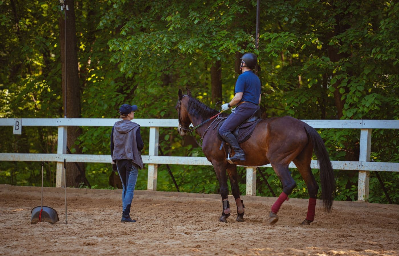 A riding instructor coaching a rider in an arena